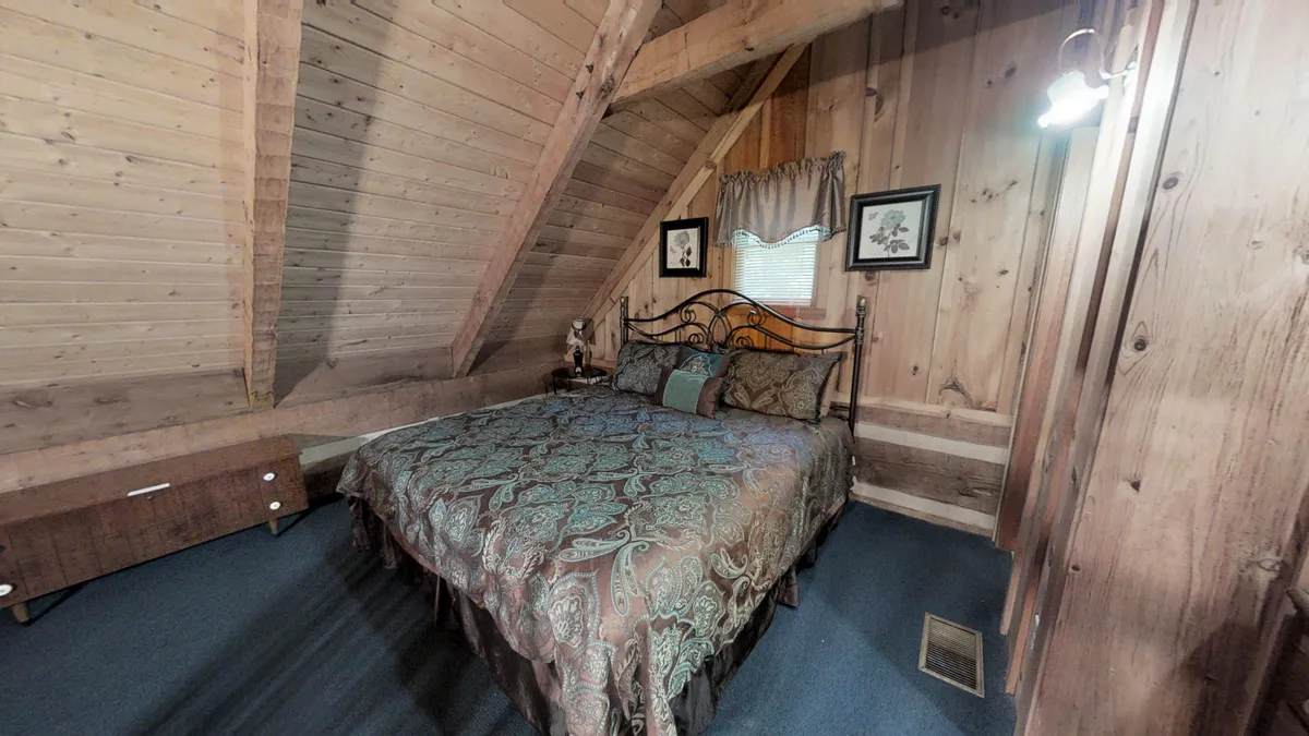 A tranquil bedroom scene with an ornate headboard, plush decorative pillows, wooded walls, and a warmly lit nightstand with a lamp. The mood is serene, emphasizing relaxation and restful nights.