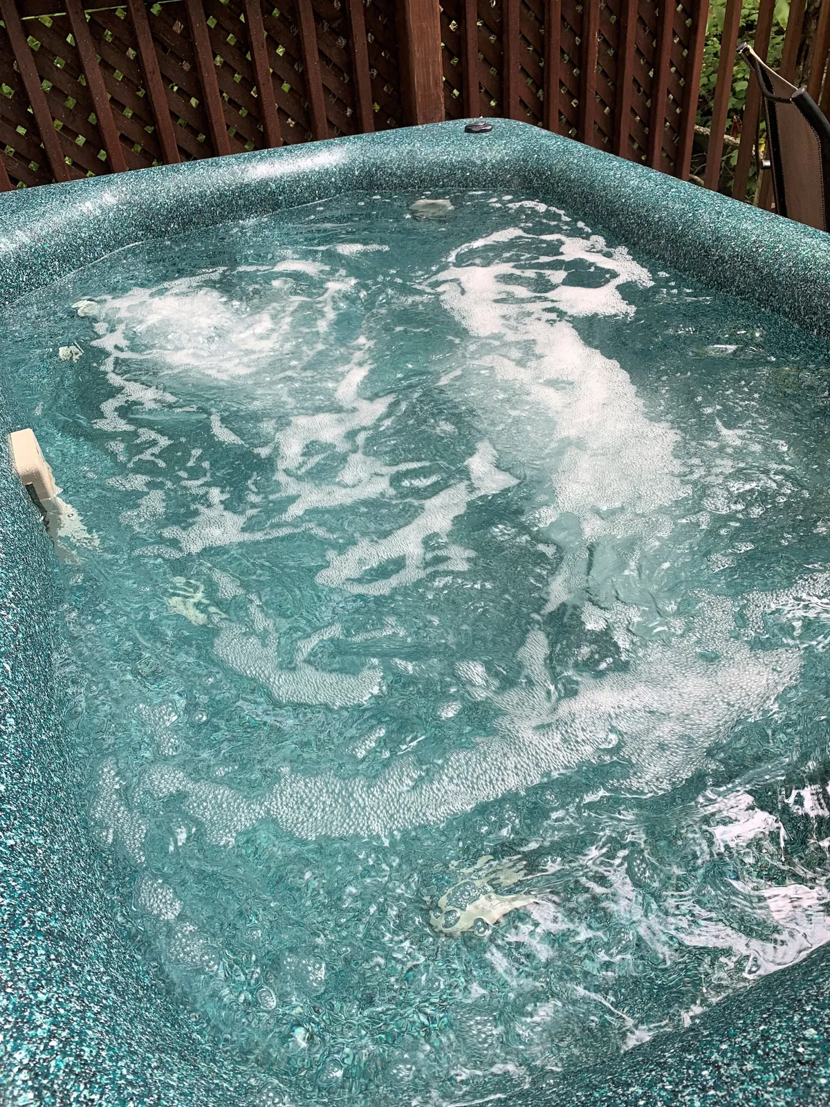 This image features a bubbling hot tub with inviting water, set against a wooden lattice backdrop. The focus is on the hot tub experience, evoking relaxation, stargazing, and time spent outdoors in comfort.