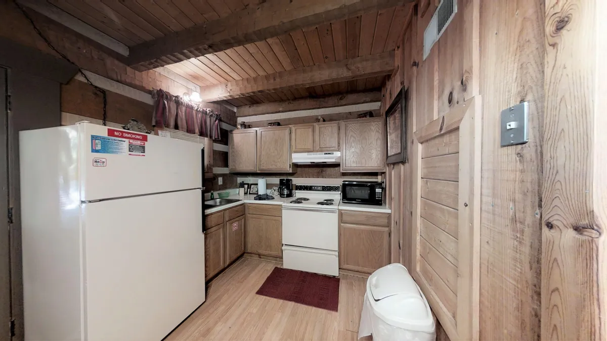 A close-up view of the kitchen showcases modern appliances, a spacious countertop, kitchen cabinets, and a cozy rug. The refrigerator and other small appliances are visible, indicating a well-equipped space perfect for any cooking task. The overall mood is homey and warm, inviting guests to prepare and enjoy meals together.