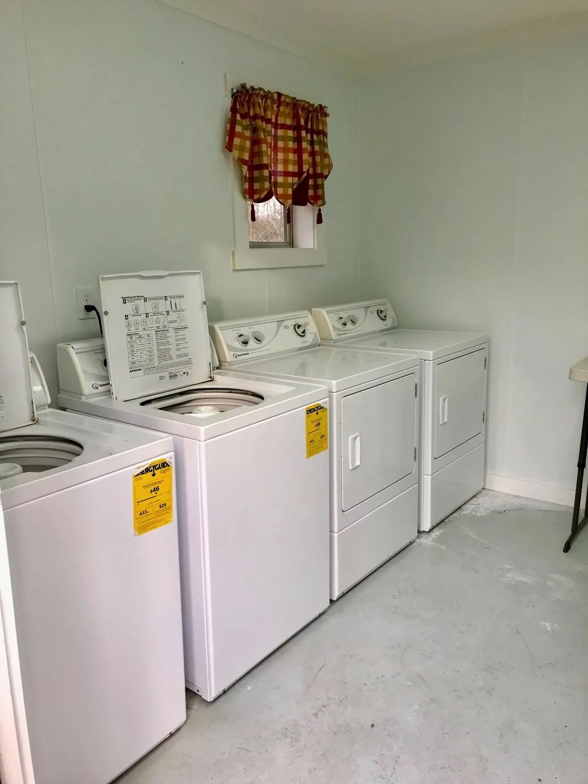 An interior view of a functional laundry area, complete with a washing machine, dryer, and homey curtains. The space is neat and practical, conveying the comforts and conveniences that make family trips easier and more enjoyable.